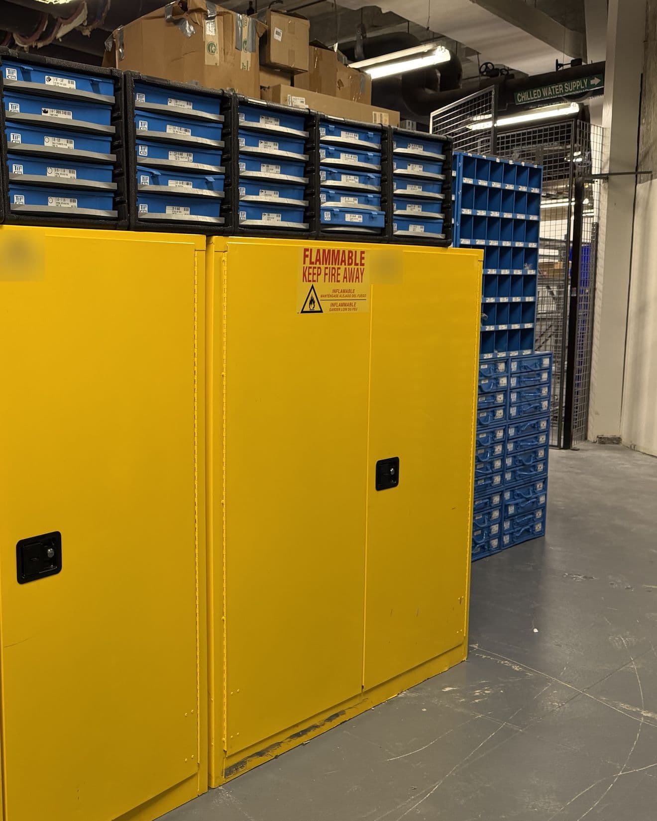 Flammable storage cabinets under rows of labeled parts drawers in a storeroom