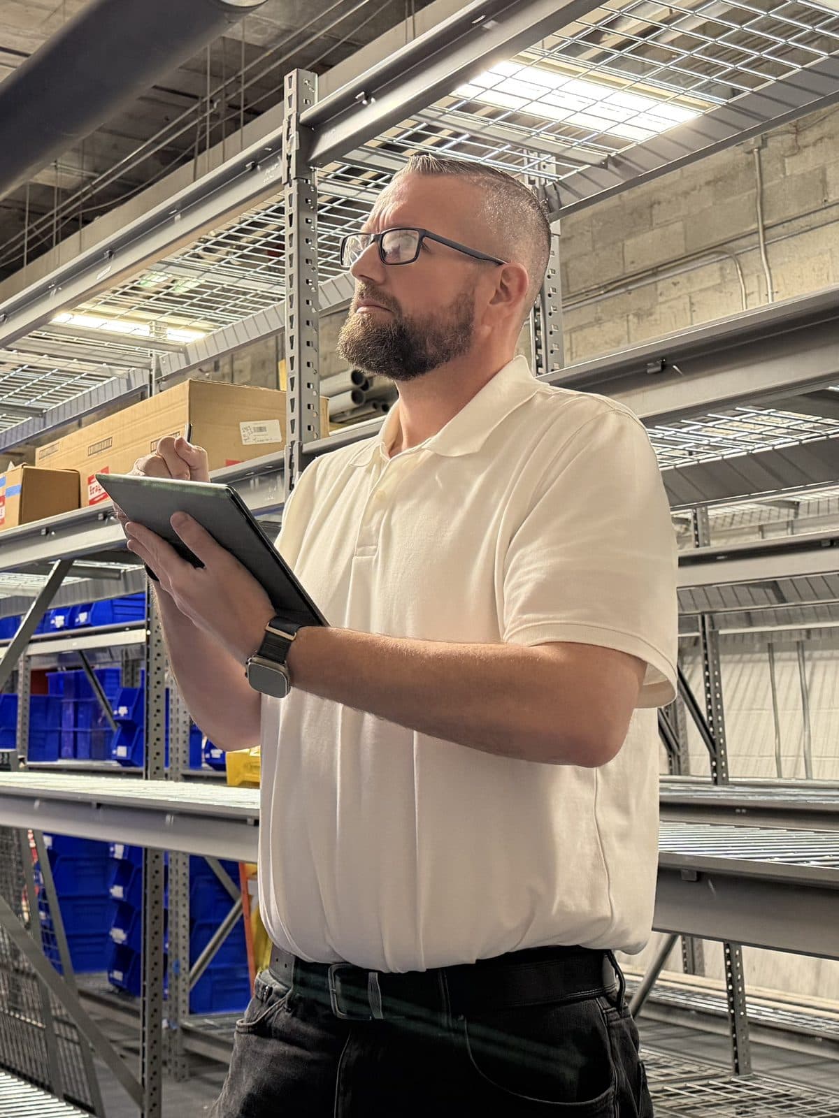 Cody Smith with a tablet, checking shelving in a storeroom