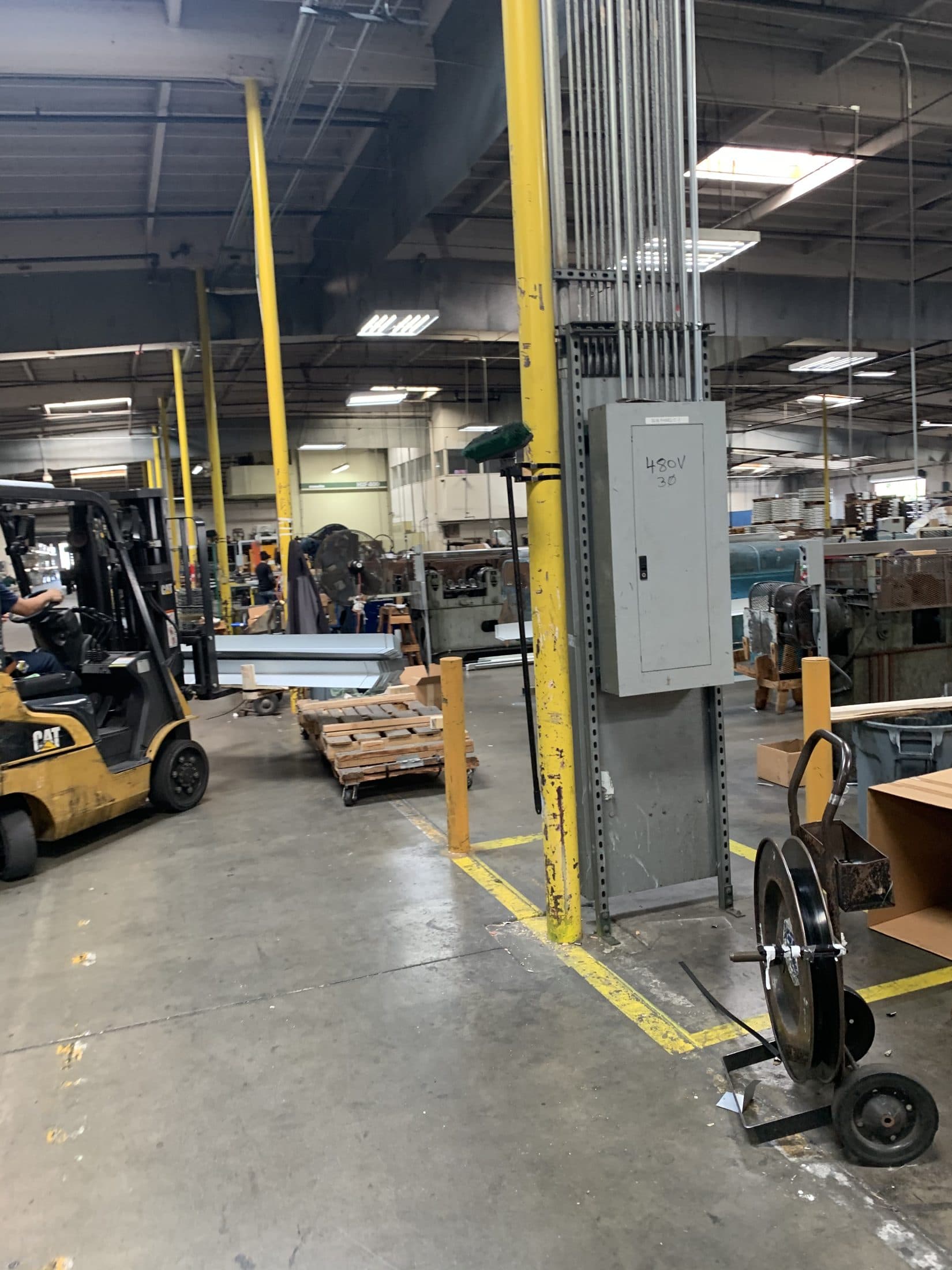 A forklift crossing a manufacturing floor past yellow safety posts