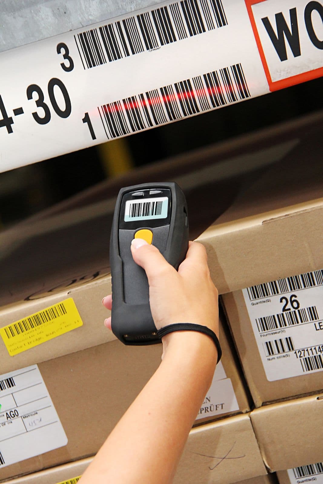 A hand scanning a carton label with a handheld barcode scanner