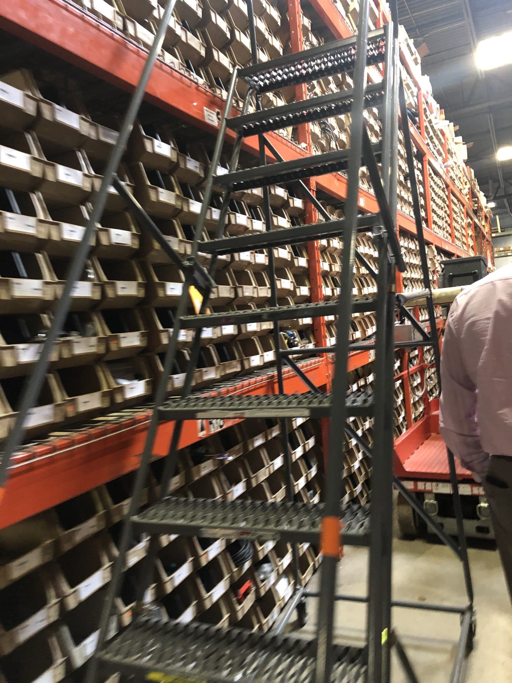 A rolling ladder in front of racks of labeled parts bins